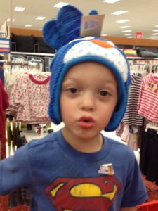 A child wearing a blue winter hat with ear flaps inside a store.