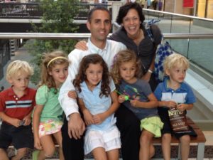 A family with four children sitting together outdoors, smiling.